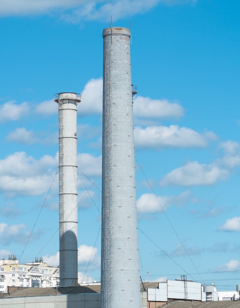 Tubi di un'impresa industriale contro un cielo blu con nuvole. Camino senza fumo