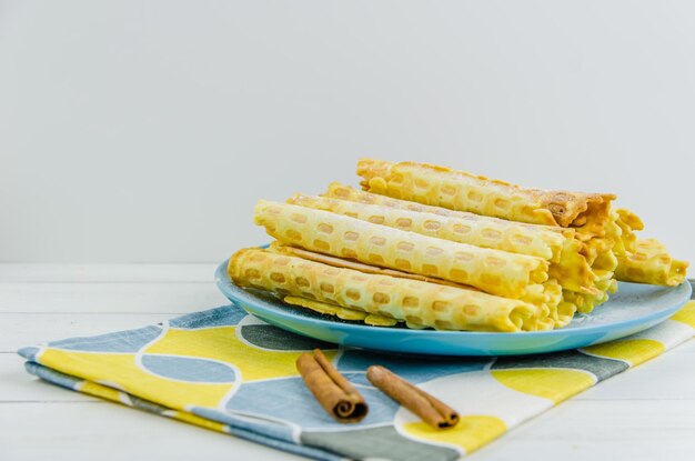 Tubi di waffle fatti in casa su un piatto blu su sfondo bianco con spazio per le copie