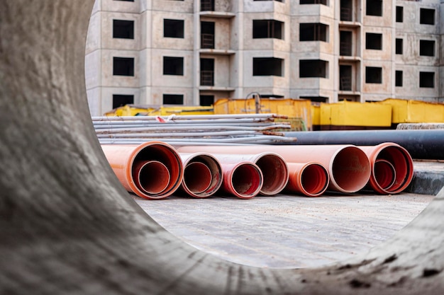 Tubi fognari arancioni giacciono su un cantiere Preparazione per i lavori di sterro per l'installazione di una condotta sotterranea