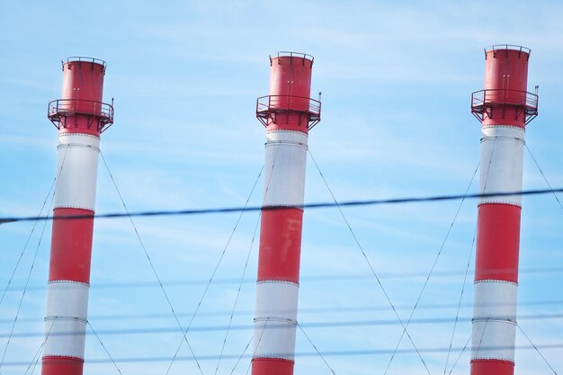 Tubi industriali sullo sfondo di fili e inquinamento ambientale del cielo blu