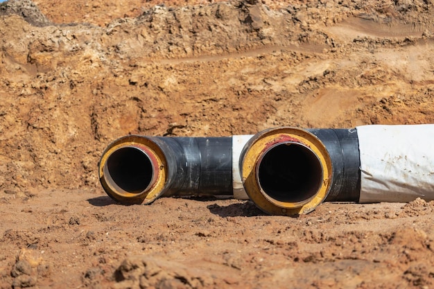 Tubo coibentato Grandi tubi metallici con guaina in plastica posata in una trincea Moderna tubazione per la fornitura di acqua calda e riscaldamento in un'area residenziale