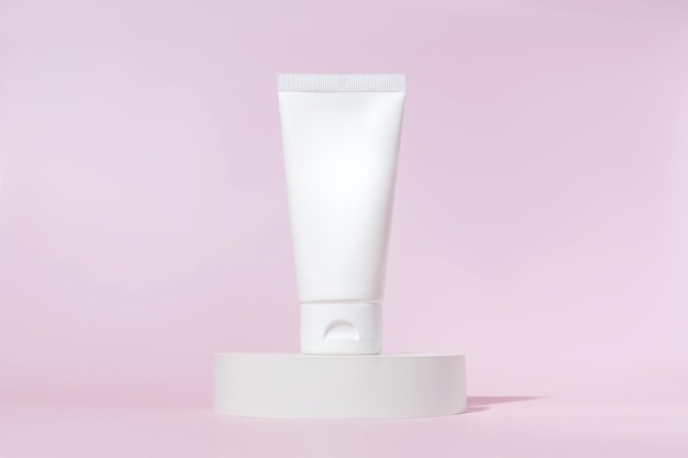 Tubo di crema con concetto di branding crema su podio in cemento su sfondo rosa Prodotto cosmetico per la cura della pelle Confezione di plastica vuota Lozione bianca senza marchio Mockup di dentifricio crema mani