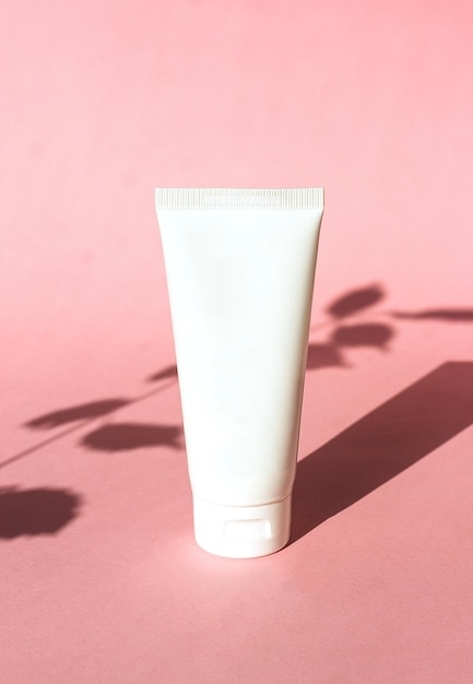 Tubo di plastica bianco per crema su sfondo rosa con prodotto cosmetico ecofriendly ombra