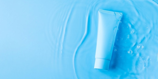 Tubo mock up con prodotto cosmetico per idratare in acqua su sfondo blu Modello per il design
