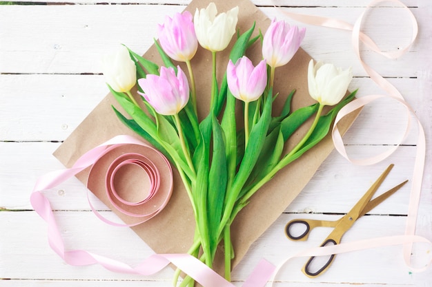 Tulipani bianchi e viola su un fondo di legno bianco.