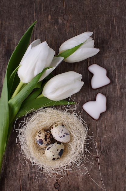 Tulipani della sorgente e uova di quaglie su una vecchia priorità bassa rustica, pasqua