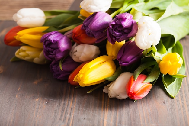 Tulipani di colore sulla tavola di legno grigia rustica. Concetto di primavera con copia spazio