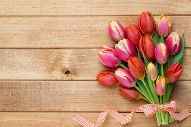 Tulipani di Pasqua della primavera nel secchio su fondo d'annata di legno.
