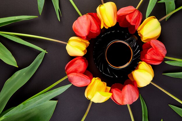 Tulipani e tazza di caffè rossi e gialli del cerchio rotondo