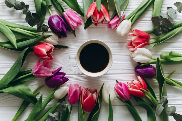 Tulipani freschi intorno a una tazza di caffè. Concetto di giorno di madri, vista dall&#39;alto.