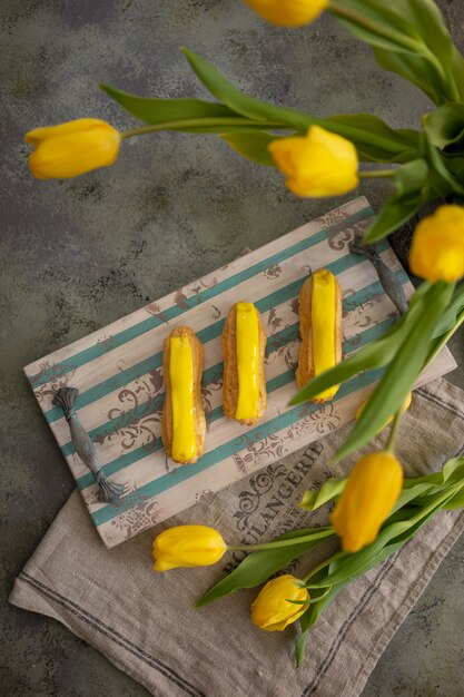 Tulipani gialli ed eclair sul vassoio in legno d&#39;epoca