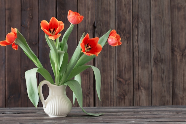 Tulipani in vaso su fondo di legno scuro