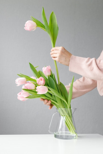 Tulipani rosa con foglie verdi in un vaso di vetro