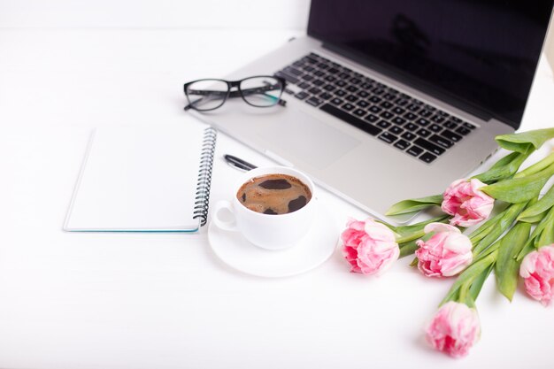 Tulipani rosa con un umore festivo e caffè su tavole di legno bianchi.