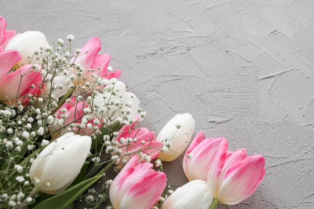 Tulipani rosa e bouquet di fiori bianchi di gypsophila su un elegante sfondo di pietra grigia fuoco selettivo Concetto di celebrazione del compleanno della festa della mamma Copia spazio per il testo