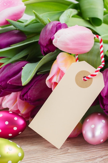 Tulipani rosa e viola con le uova di Pasqua e la nota di carta vuota