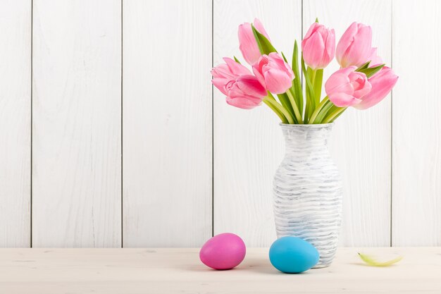 Tulipani rosa freschi e uova di Pasqua su legno