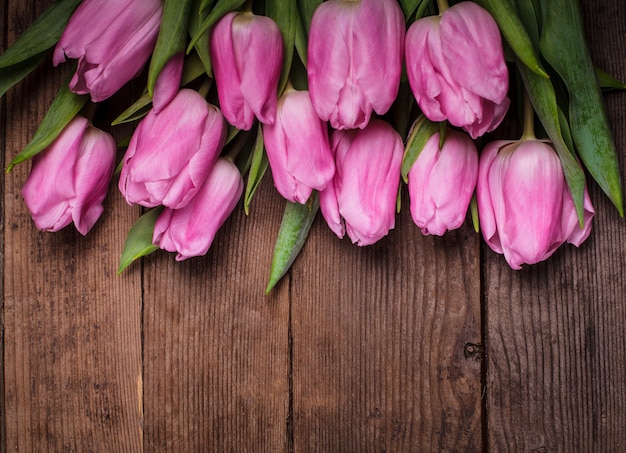 Tulipani rosa su squallido tavolo di legno bianco