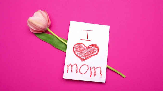 Tulipano rosa con carta I love mom su di esso. Sfondo rosa