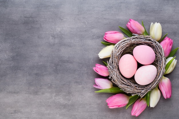 Tulipano rosa con uova rosa nidificano su uno sfondo grigio. Biglietto di auguri di Pasqua.