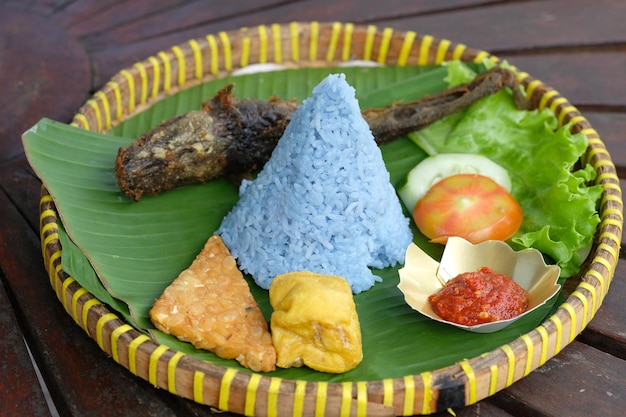 Tumpeng lele goreng. riso a forma di cono con pisello farfalla, pesce gatto fritto, tofu tempeh fritto, sambal.