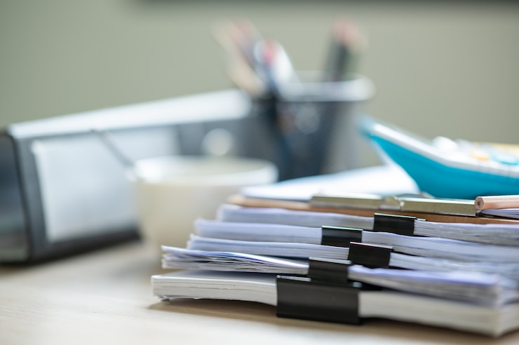 Photo tumpukan dokumen dengan folder klip kertas diletakkan di meja bisnis di kantor bisnis.
