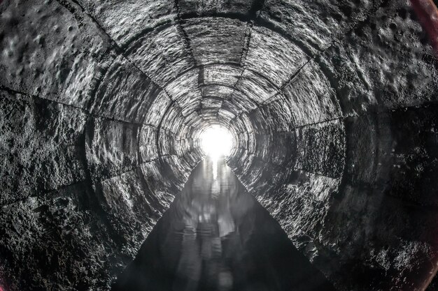 Tunnel di drenaggio rotondo in cemento con acqua costruito con cassaforma Con luce all'estremità Fiume sotterraneo nascosto nel tubo