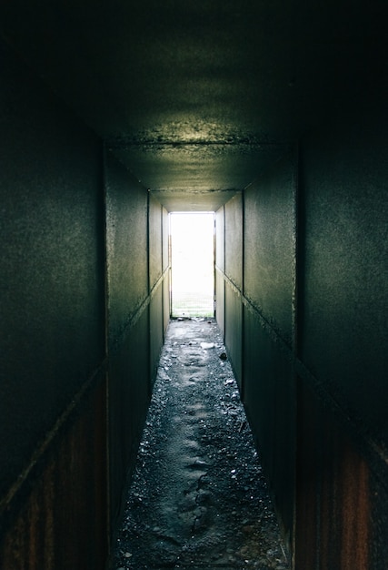 Tunnel scuro metallico abbandonato con luce diurna alla fine