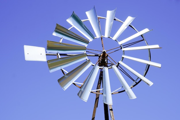 Turbina eolica d'annata del piccolo mulino a vento rustico in cielo blu