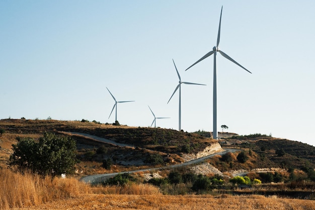 Turbina eolica in campo. Generatore eolico. Centrale eolica. Energia elettrica. Strada in campo. La Natura Di Cipro. Strada attraverso le turbine eoliche. Elettricità dal vento