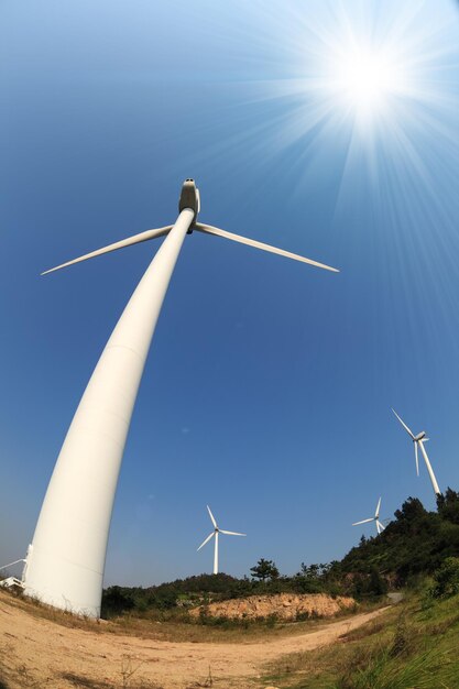 Turbine eoliche sotto il cielo blu con raggi solari