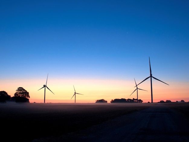 Turbine eoliche sul paesaggio contro il cielo blu al tramonto.