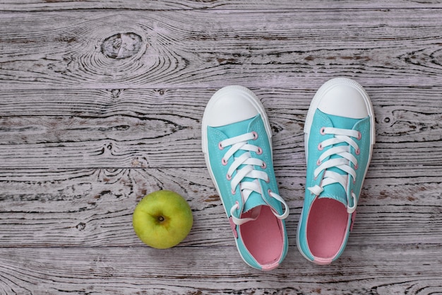 Turchese con scarpe da ginnastica rosa e una mela sul pavimento di legno.