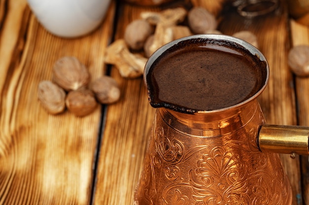 Turco di rame brillante con caffè preparato sulla tavola di legno marrone