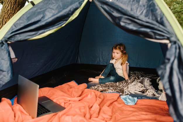 Turismo per bambini. Bambino che utilizza computer portatile nella tenda al campeggio.