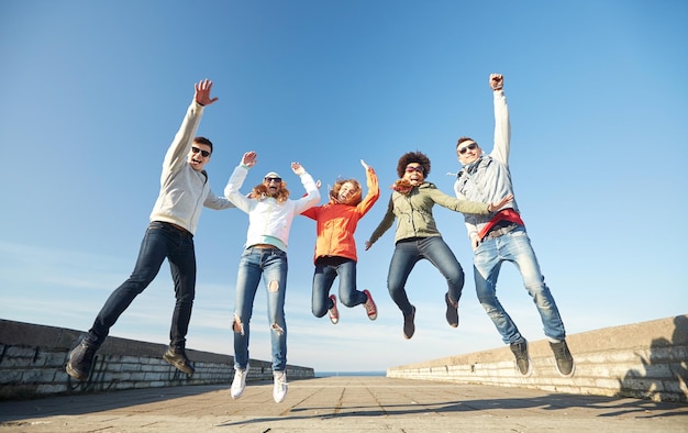 turismo, viaggi, persone, tempo libero e concetto adolescenziale - gruppo di amici felici in occhiali da sole che si abbracciano e ridono sulla strada della città