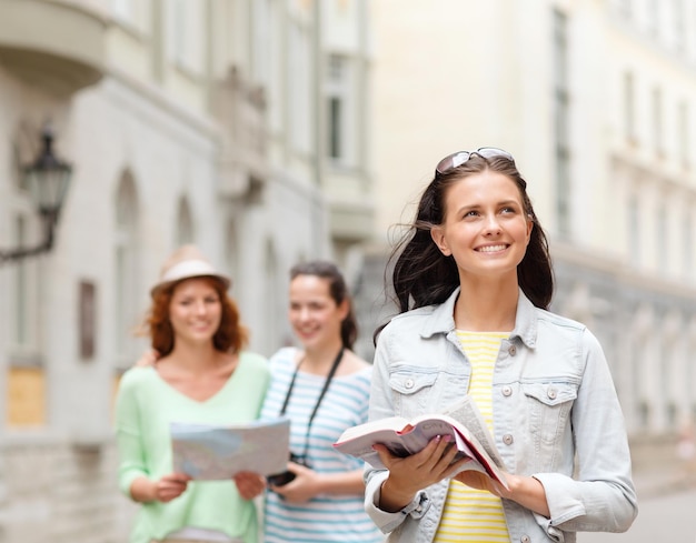 turismo, viaggi, tempo libero e vacanze e concetto di amicizia - ragazze adolescenti sorridenti con guida della città, mappa e fotocamera all'aperto