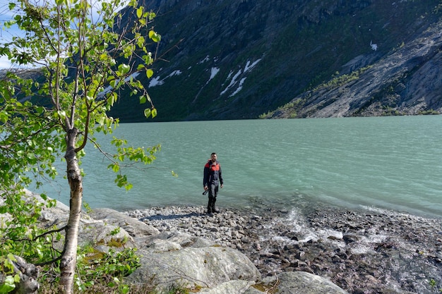Turista al lago del ghiacciaio Nigardsbreen con la macchina fotografica in mano in Norvegia