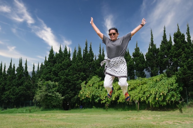 Turista asiatica che salta nel parco per farsi fotografare