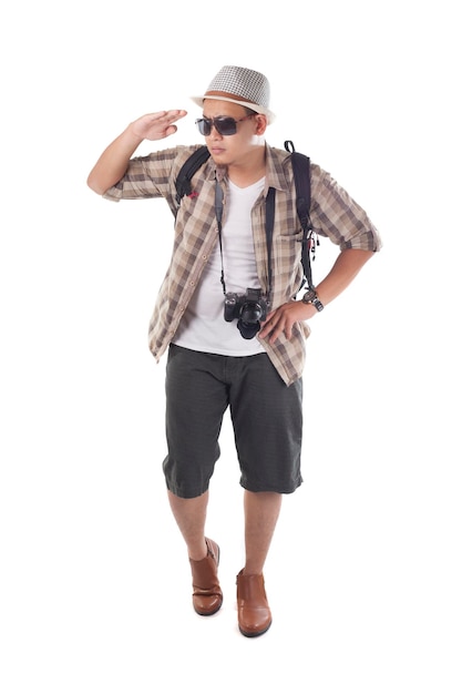 Turista asiatico a zaino in spalla con cappello, occhiali da sole neri, fotocamera e zaino a spalla che guarda in lontananza