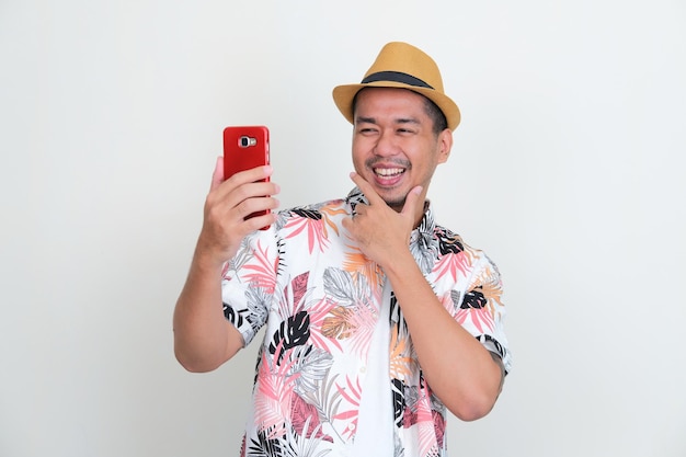Turista asiatico che fa un selfie usando il suo cellulare con un'espressione felice