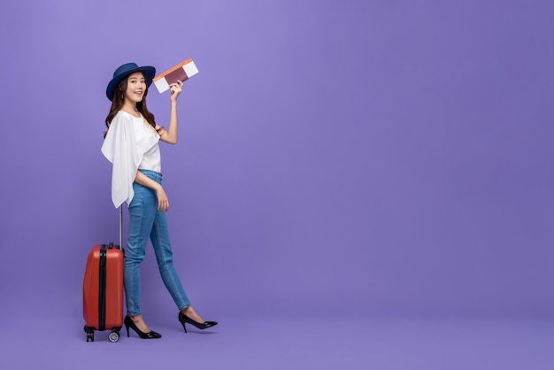 Turista asiatico della donna con bagaglio che mostra passaporto e carta d'imbarco