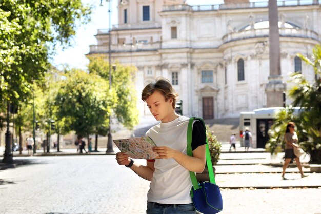 Turista che guarda la mappa giovane che cammina in città