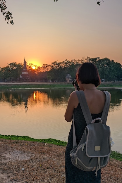 turista che scatta foto al tramonto al parco storico di Sukhothai in Thailandia