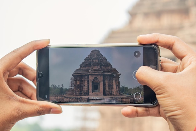 Turista che scatta foto con il cellulare al luogo del turismo indiano del tempio del sole di Konark