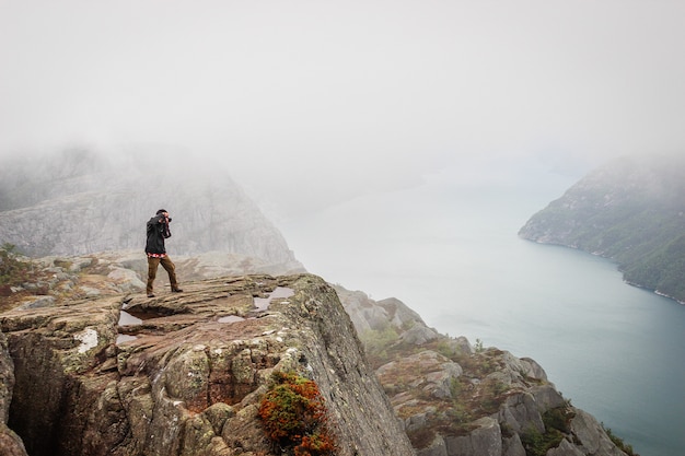 Turista del fotografo della natura con i tiri della macchina fotografica mentre stando sulla montagna.