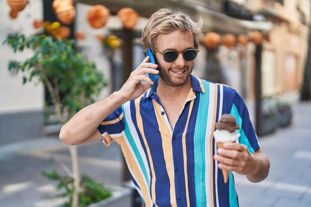 Turista del giovane che parla sullo smartphone che mangia il gelato alla via