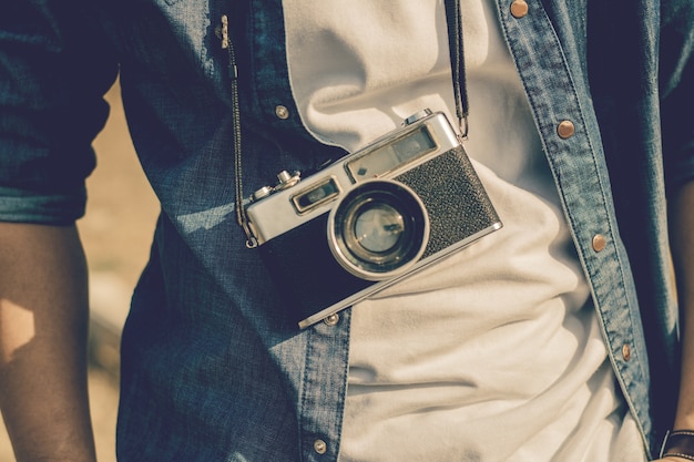 Turista del giovane che sta e che prende le foto con la macchina fotografica d&#39;annata.