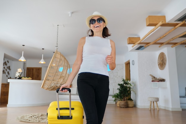 Turista dell'ospite della donna con la valigia nell'interno della hall dell'hotel. Bella donna matura in viaggio, moderna sala del resort termale dell'hotel, persone in età di svago e fine settimana