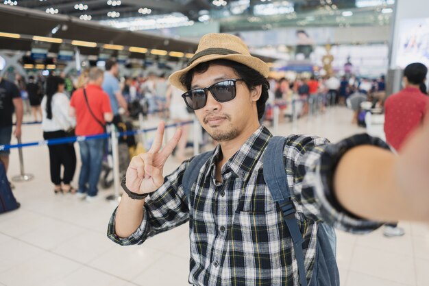 Turista dell&#39;uomo asiatico che prende un selfie con la macchina fotografica dello Smart Phone in aeroporto.